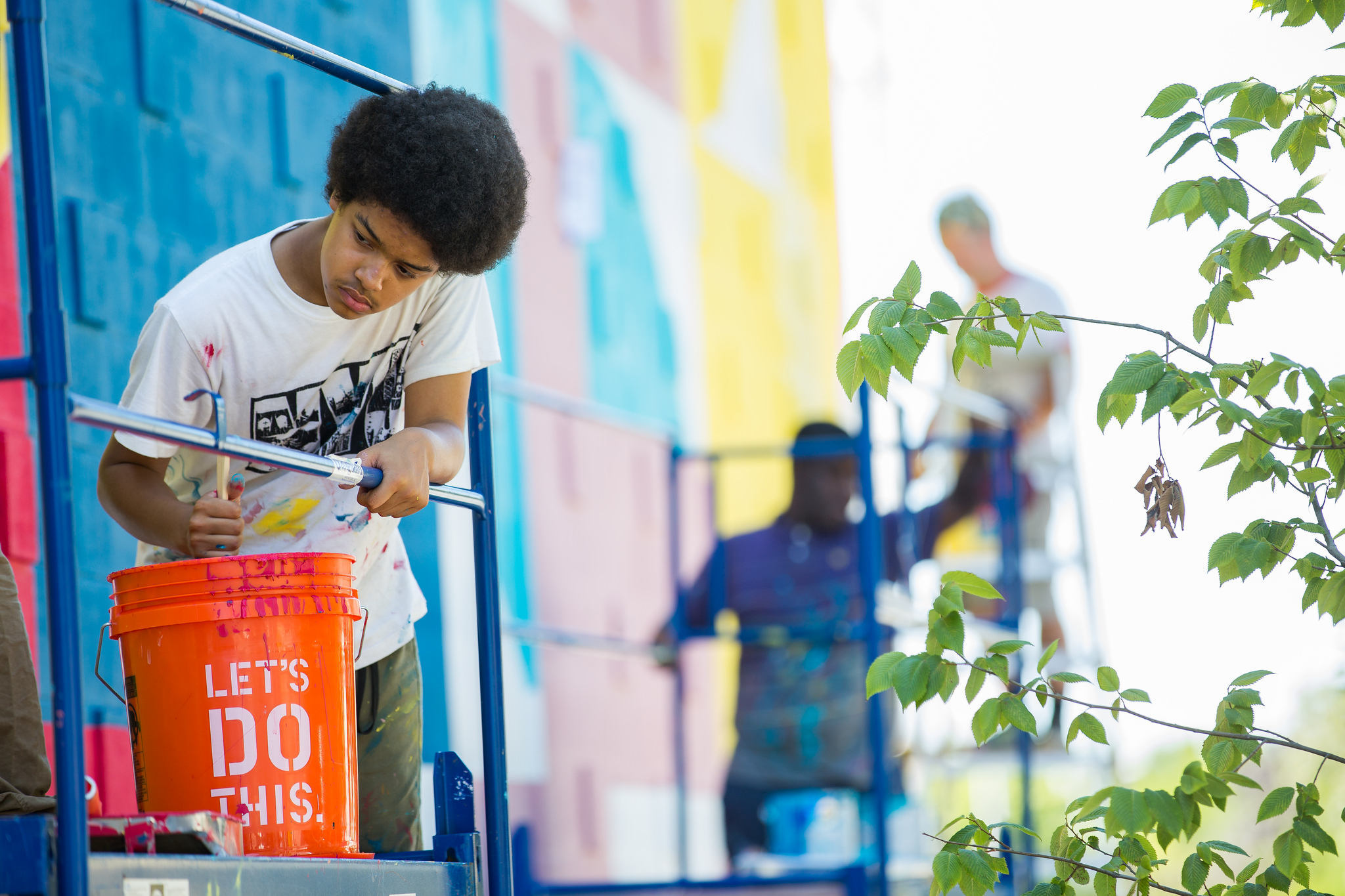 a young boy is painting a mural on a wall.