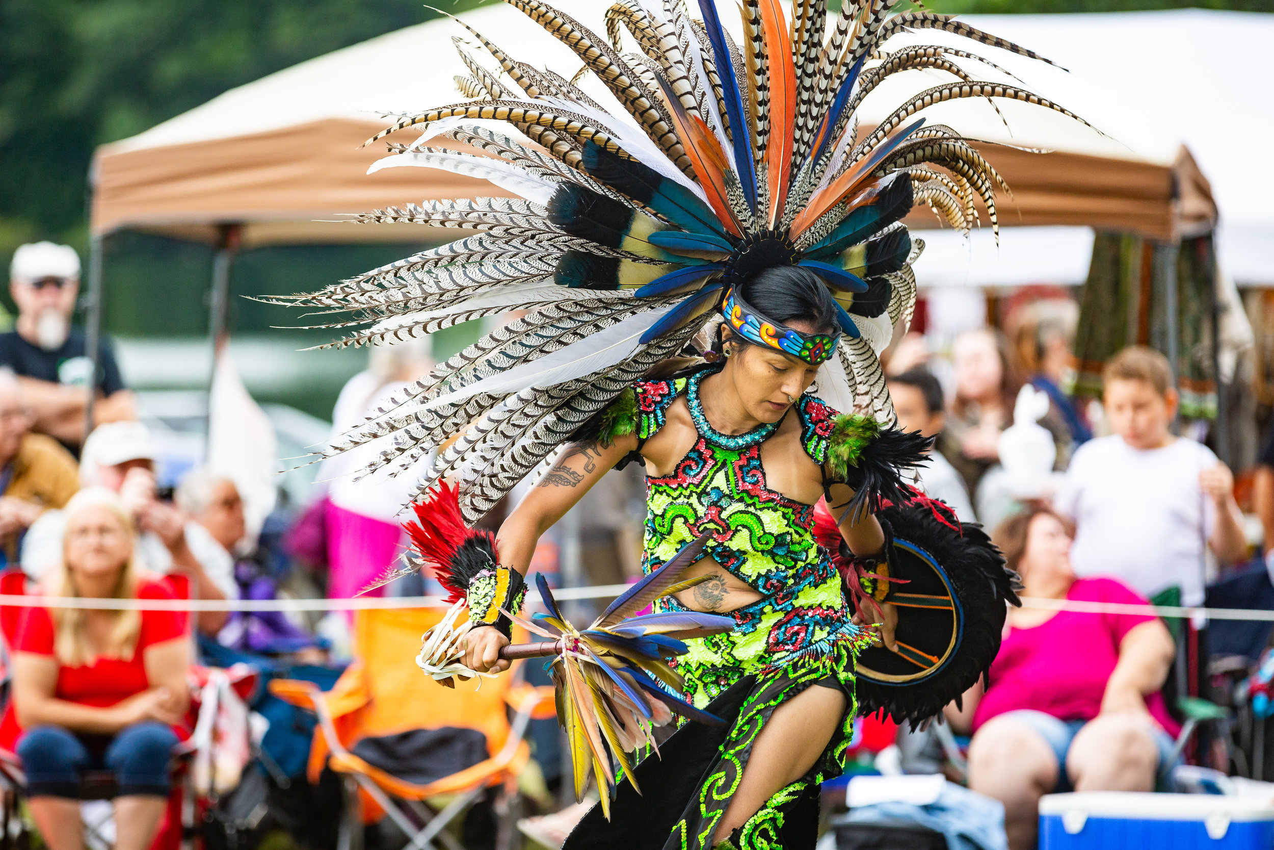 a woman in a colorful costume dancing in front of a crowd.