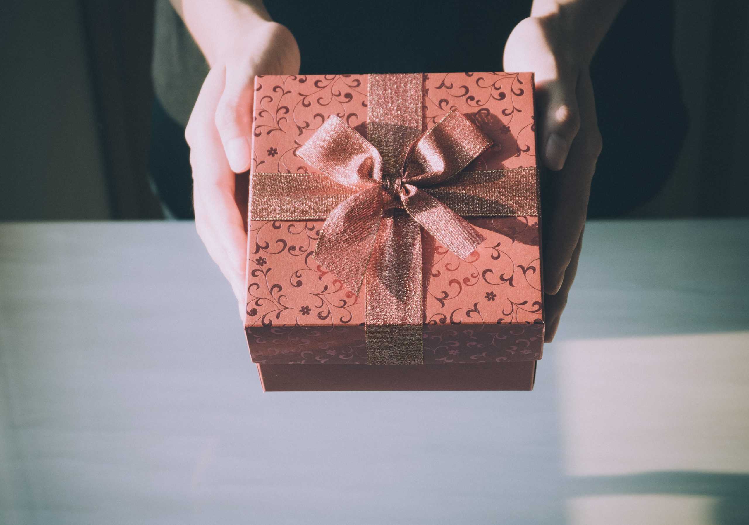 a person holding a red gift box with a bow.