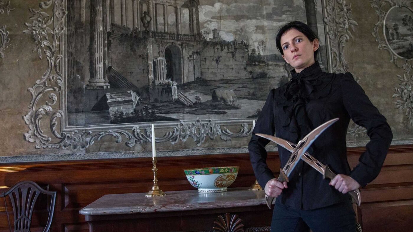 a woman standing in front of a painting holding a knife.