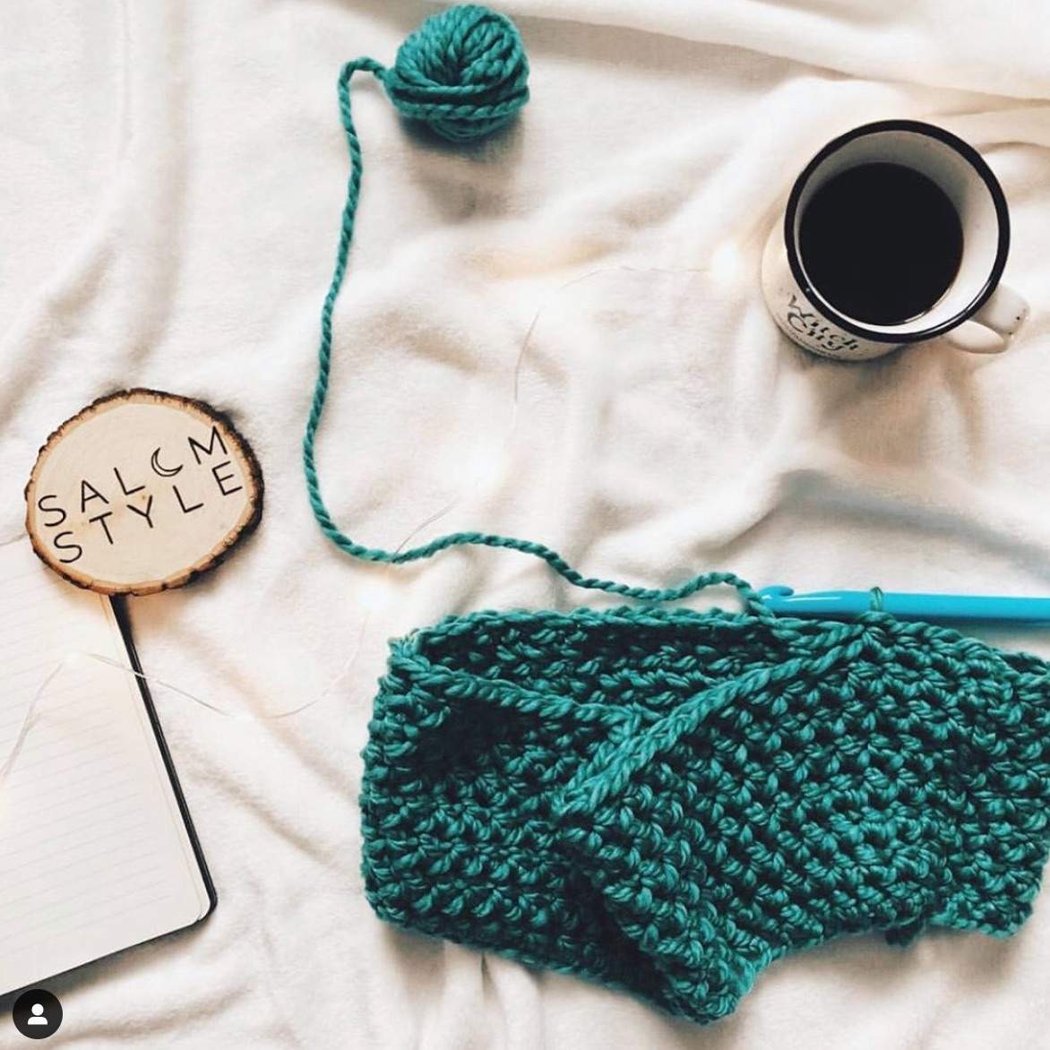 a cup of coffee next to a knitted item.