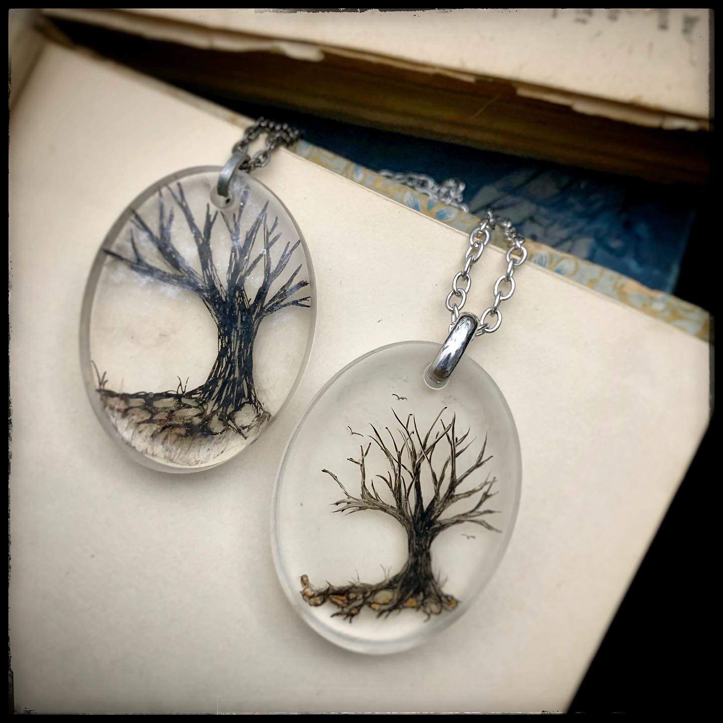 a couple of necklaces with a tree inside of it.