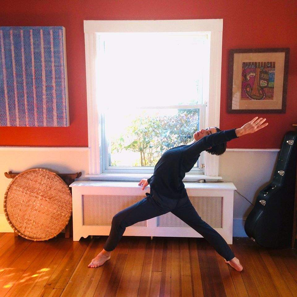 a woman in a yoga pose in front of a window.