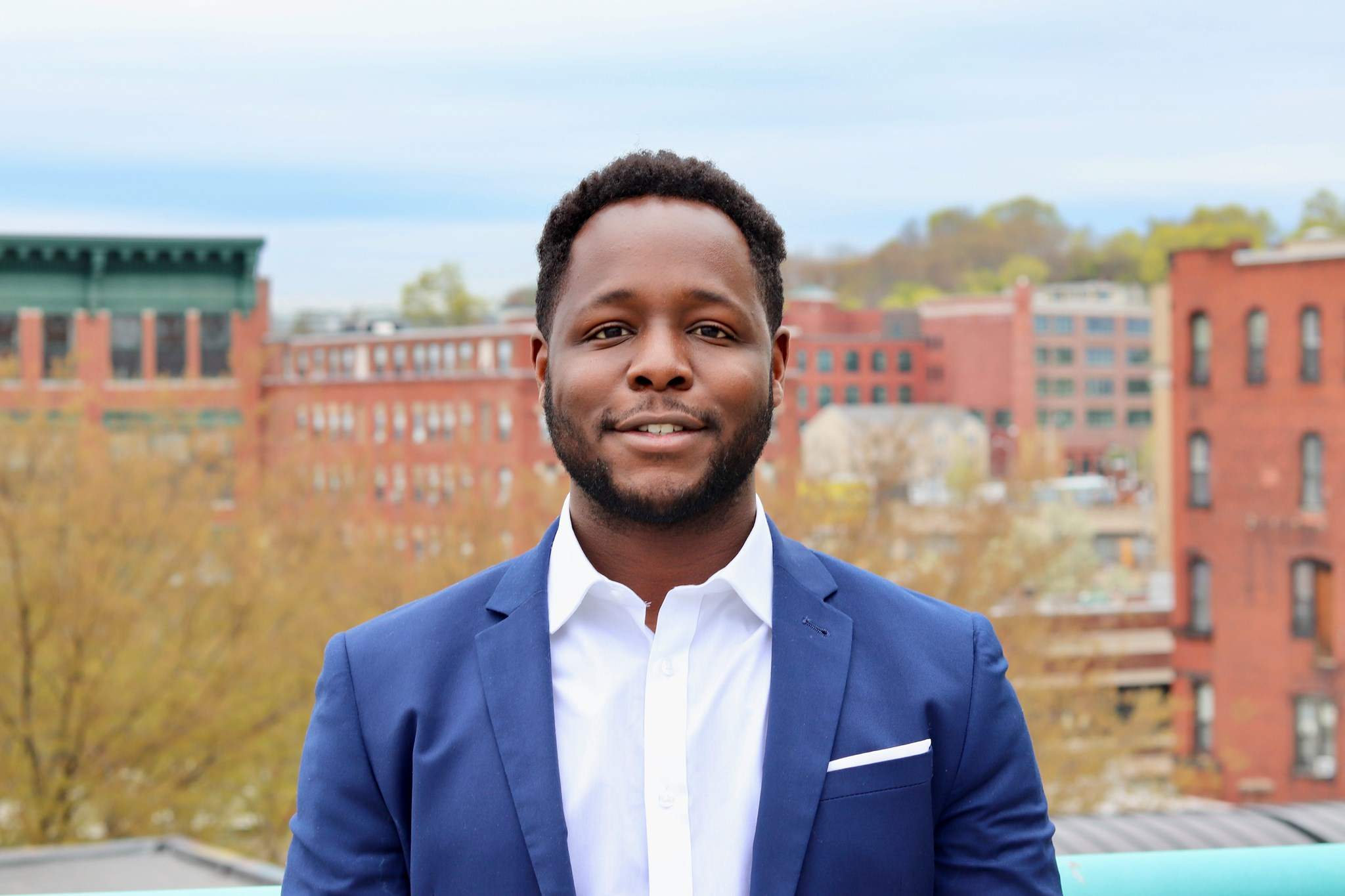 a man in a blue suit standing in front of a building.
