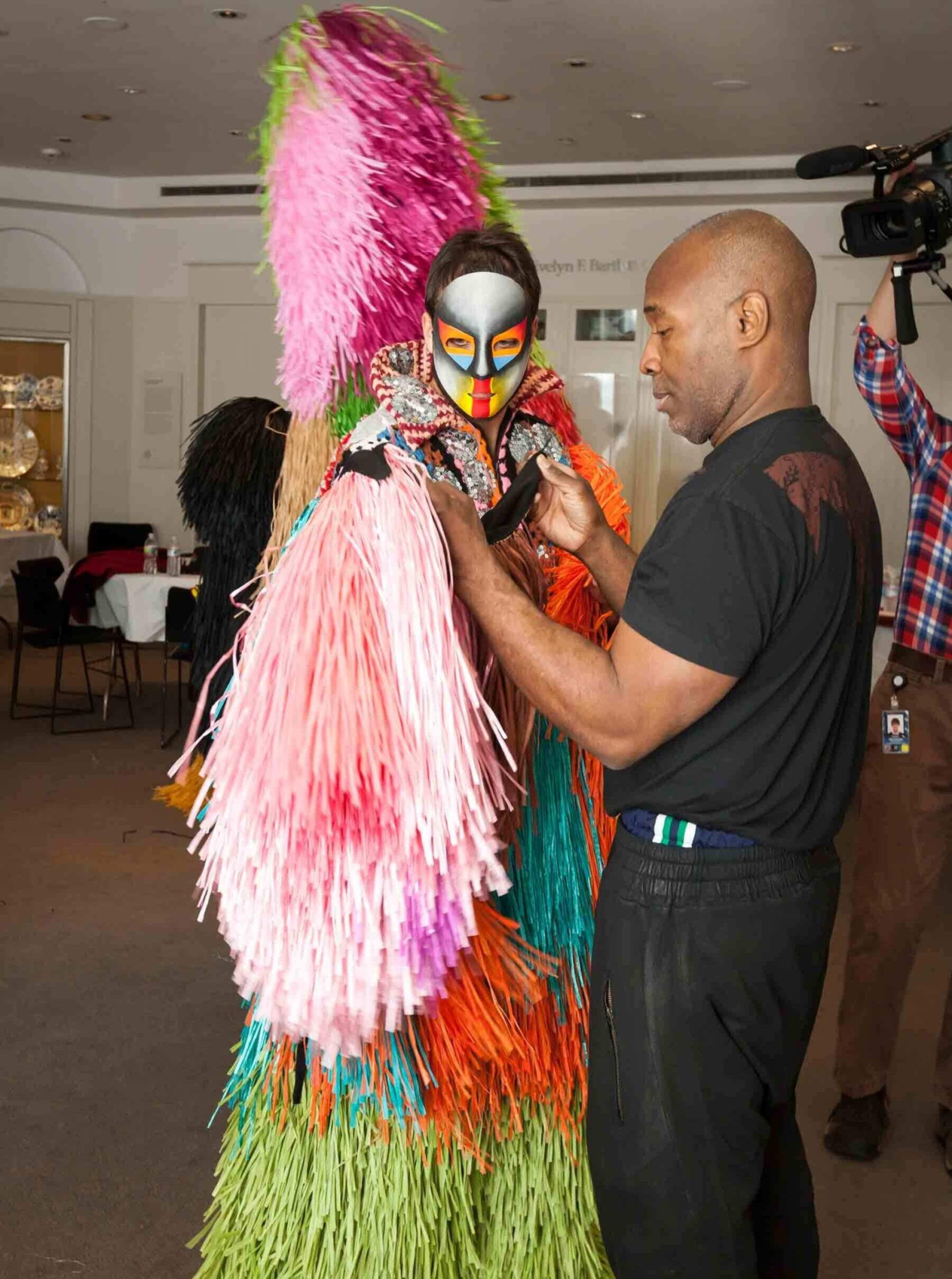 a man standing next to a woman in a colorful costume.