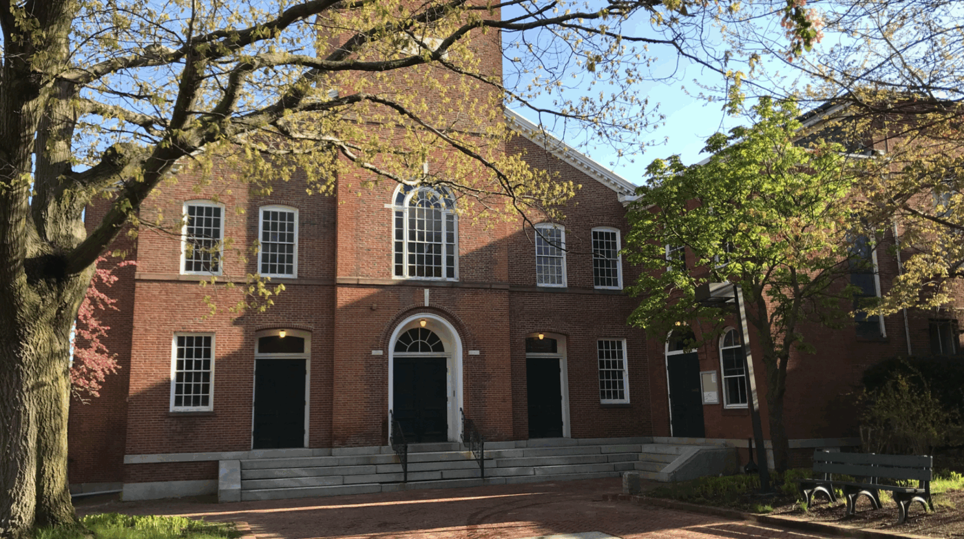 Salem Playhouse’s vibrant red brick exterior, arched doors, and sunny windows welcome our Essex County community amid blooming trees.