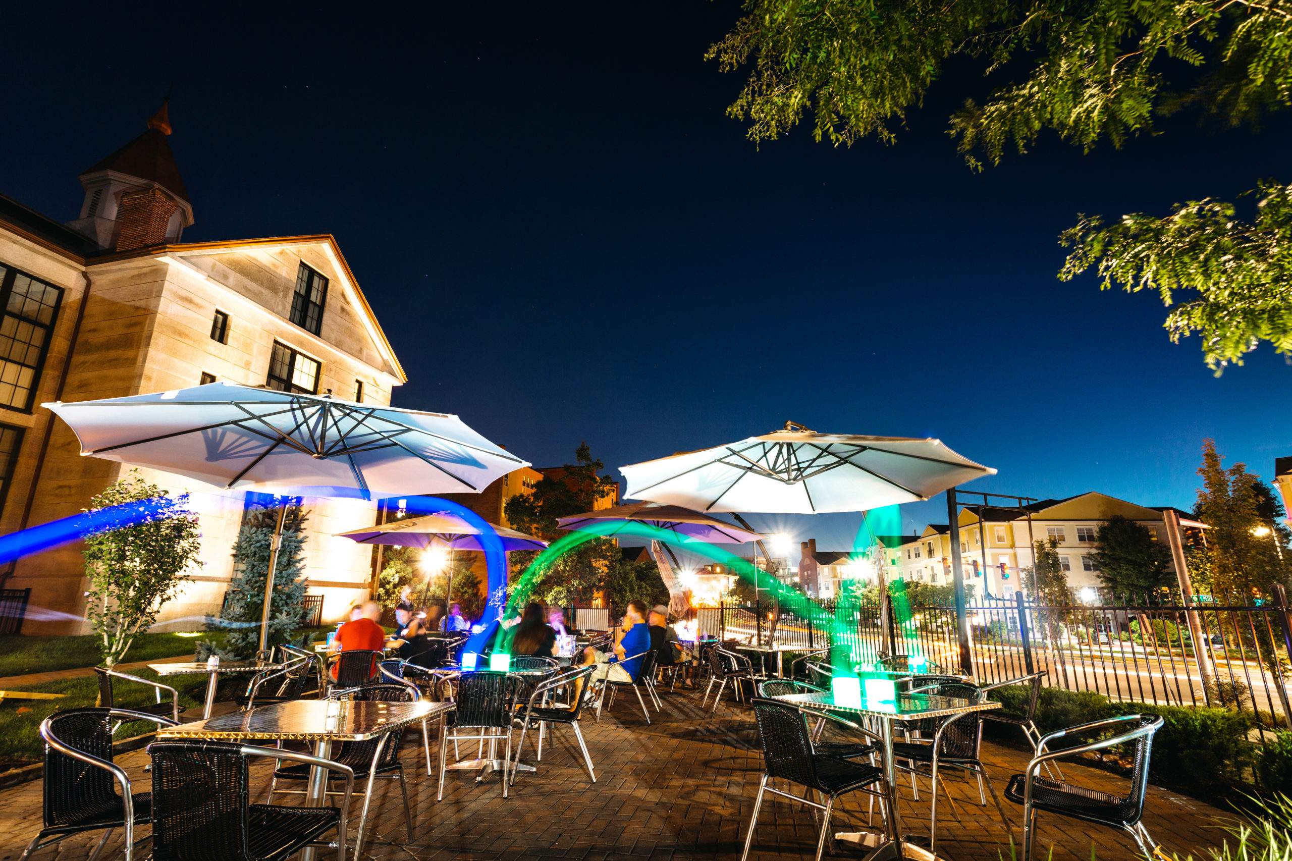 a group of people sitting at tables under umbrellas.
