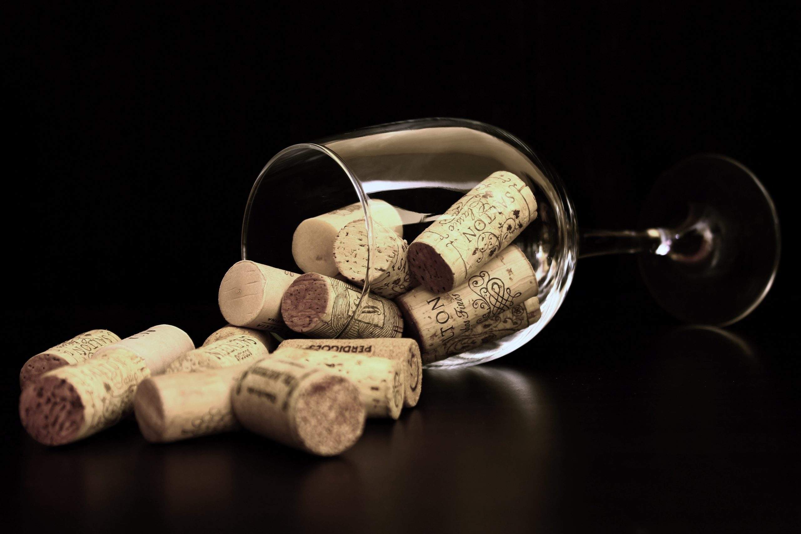 a wine glass filled with wine corks on top of a table.