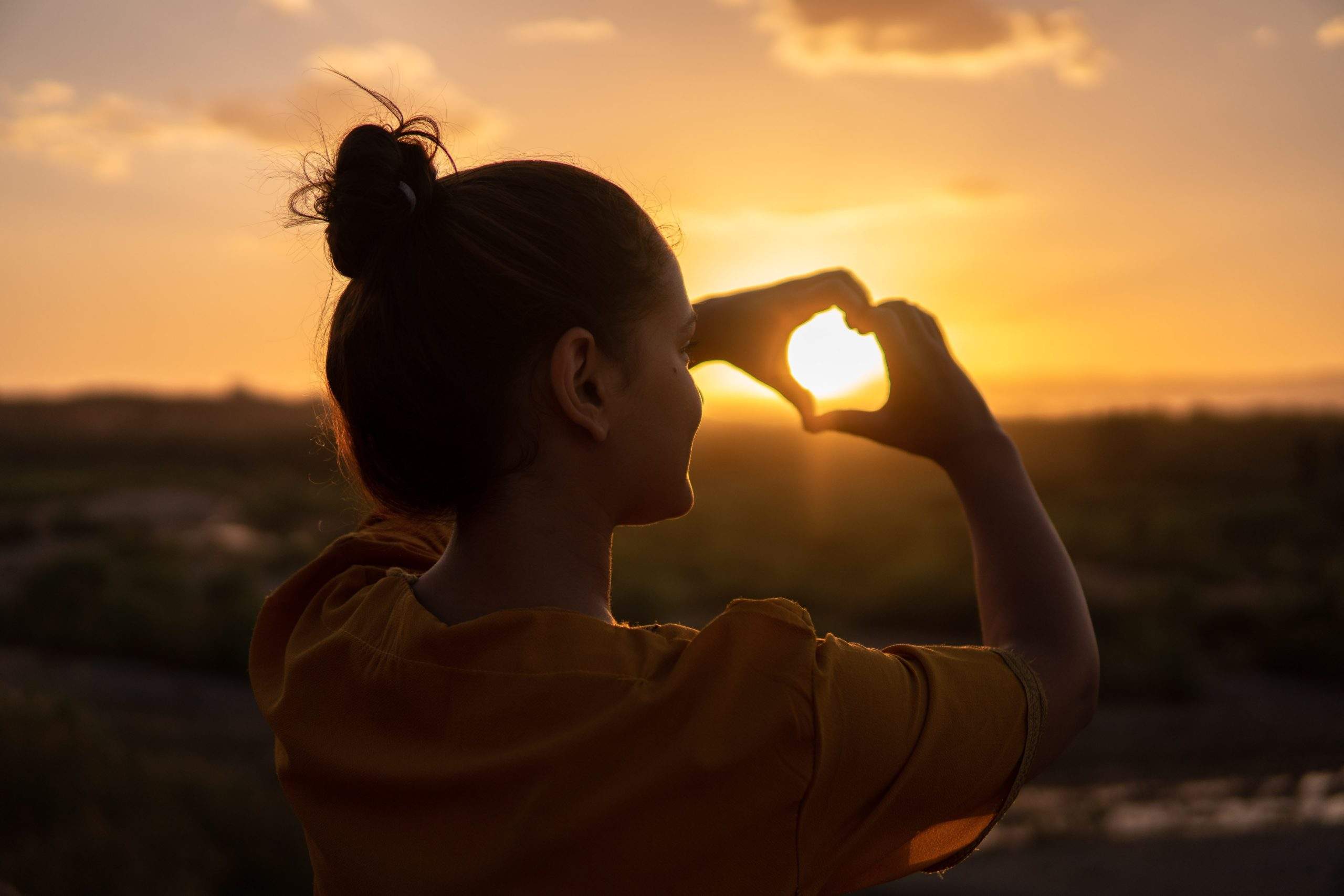 a woman looking into the distance with a sunset in the background.