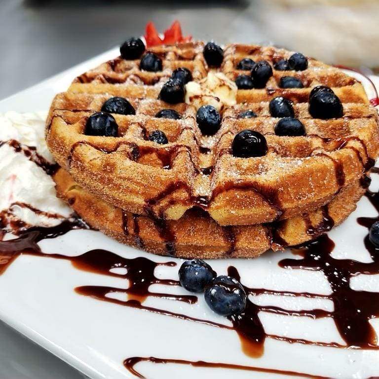 a waffle topped with blueberries and whipped cream.