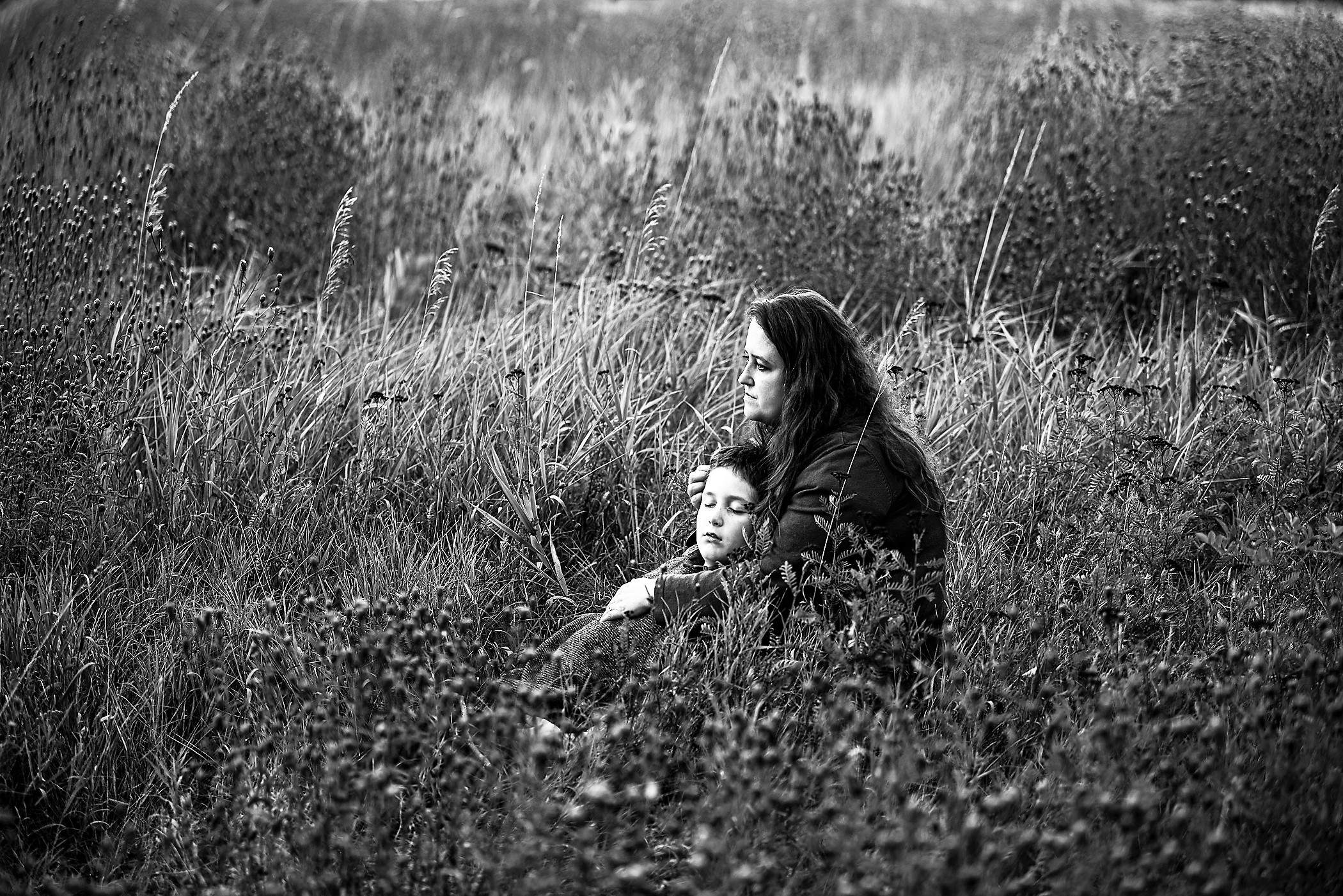 a woman and a child are sitting in a field.