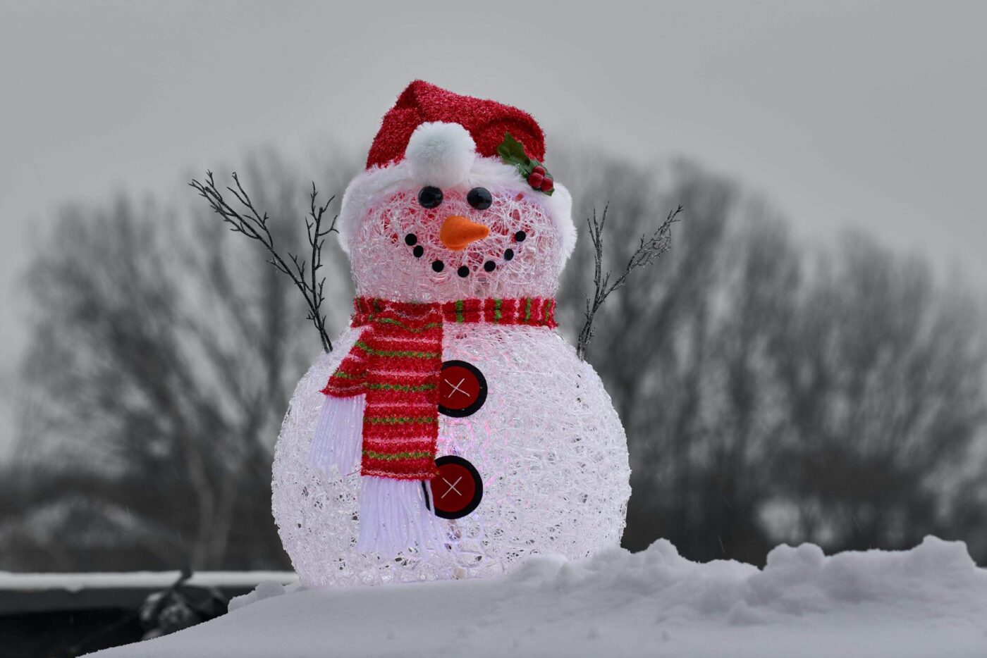 a snowman with a red hat and scarf standing in the snow.