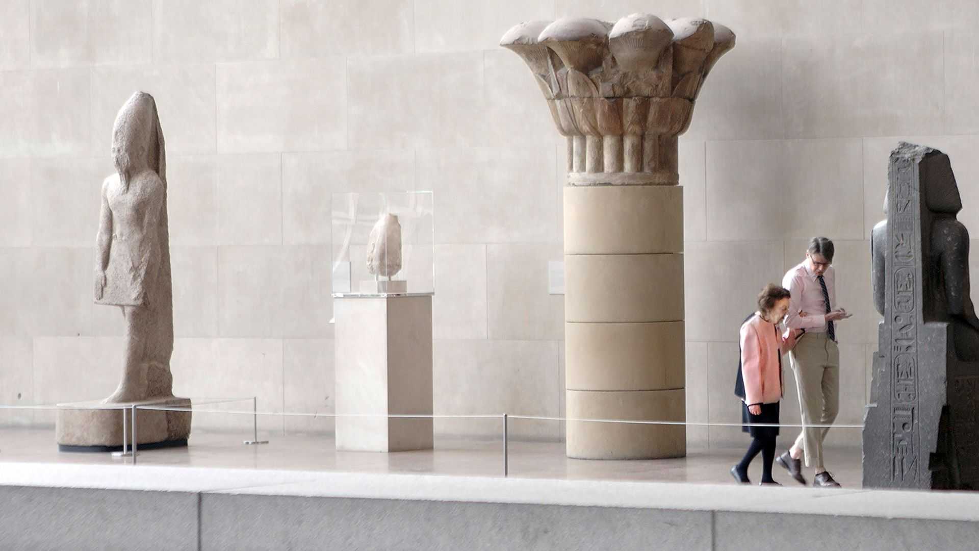 a man and a woman standing in front of statues.