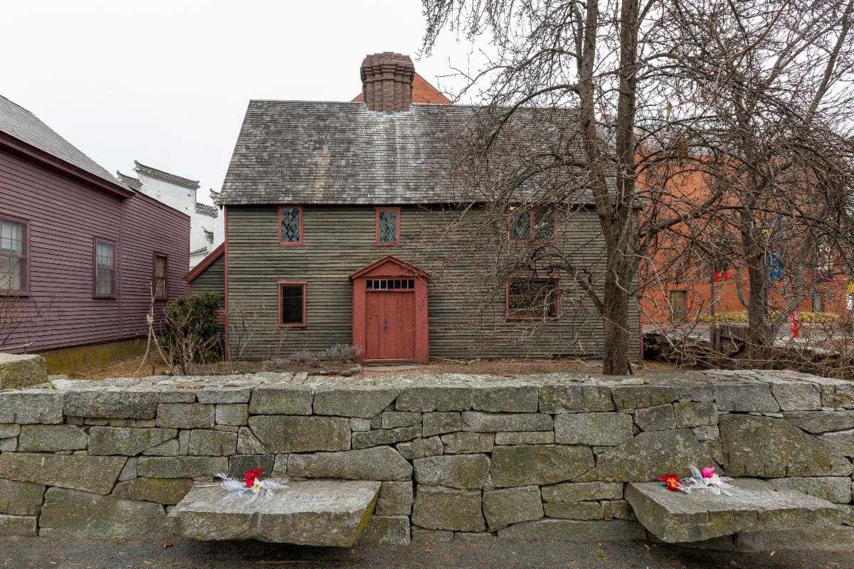 a stone wall with benches in front of a house.