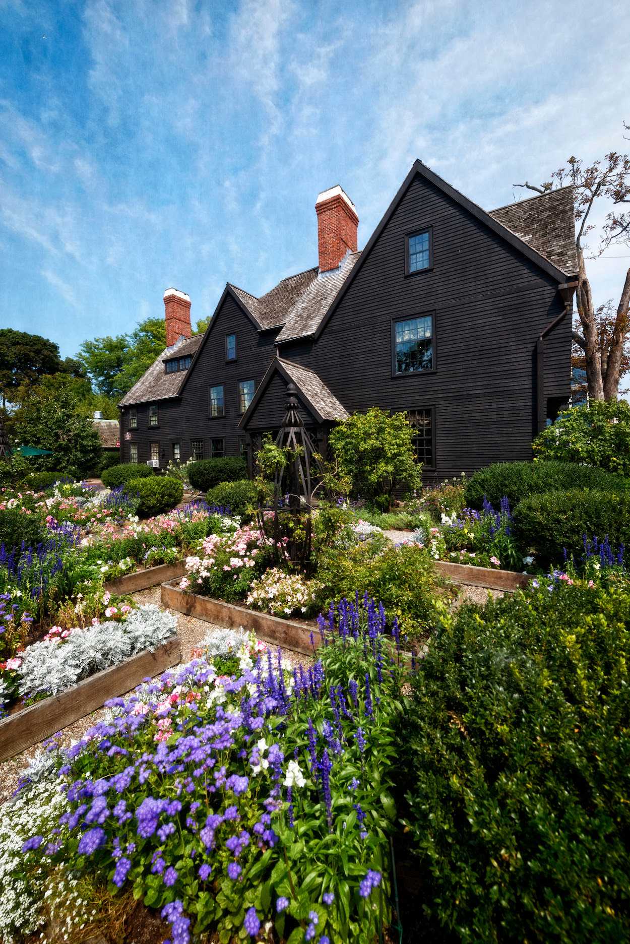 a black house with a garden of flowers in front of it.