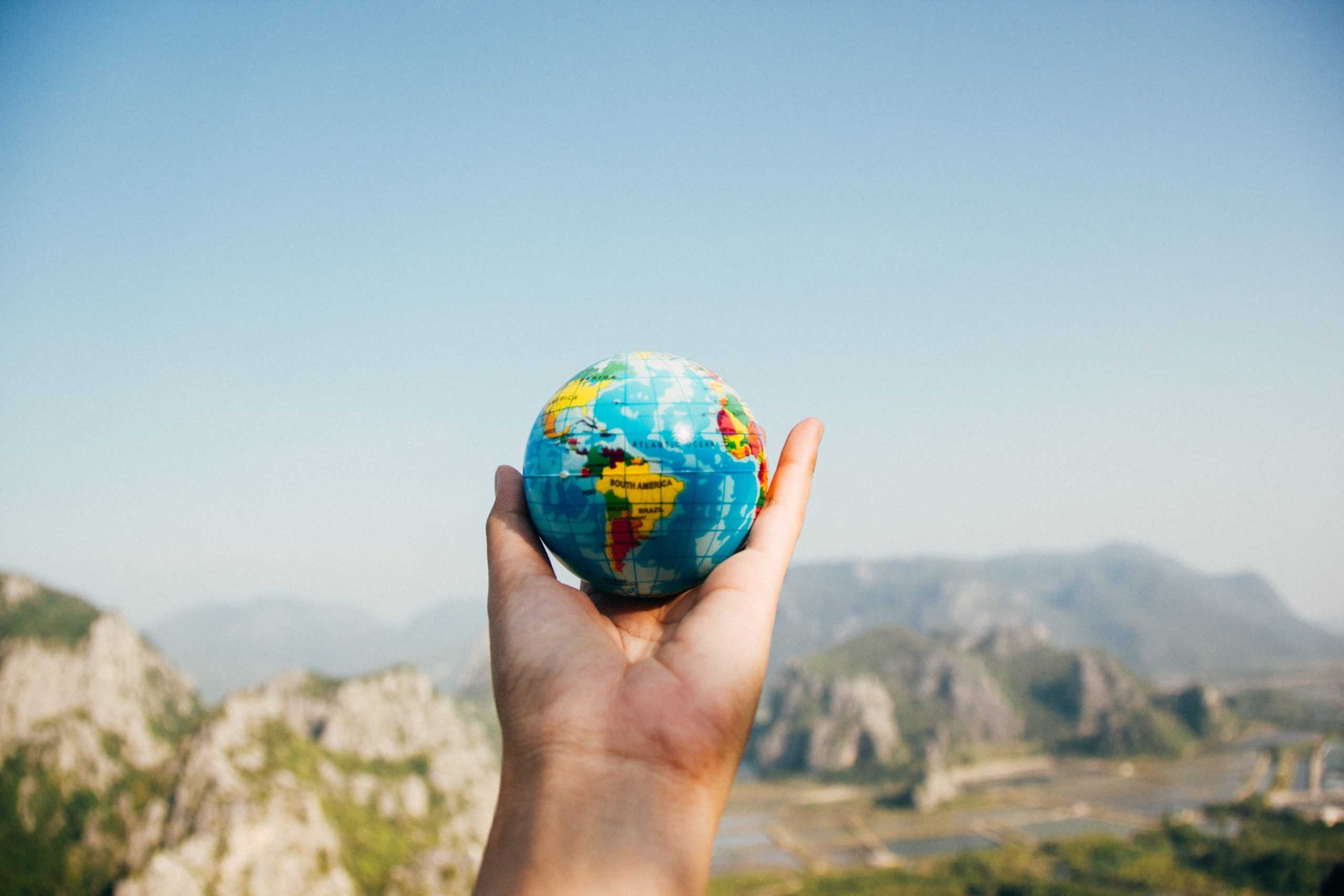 a person holding a small globe in their hand.