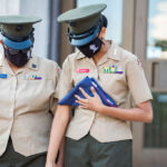 two female police officers in uniform are holding folders.