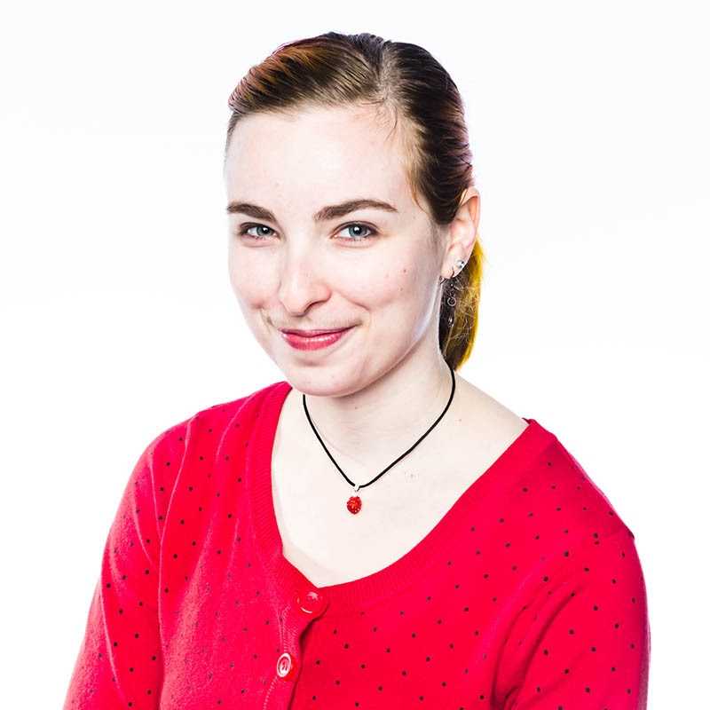 a woman wearing a red shirt and a pair of earrings.