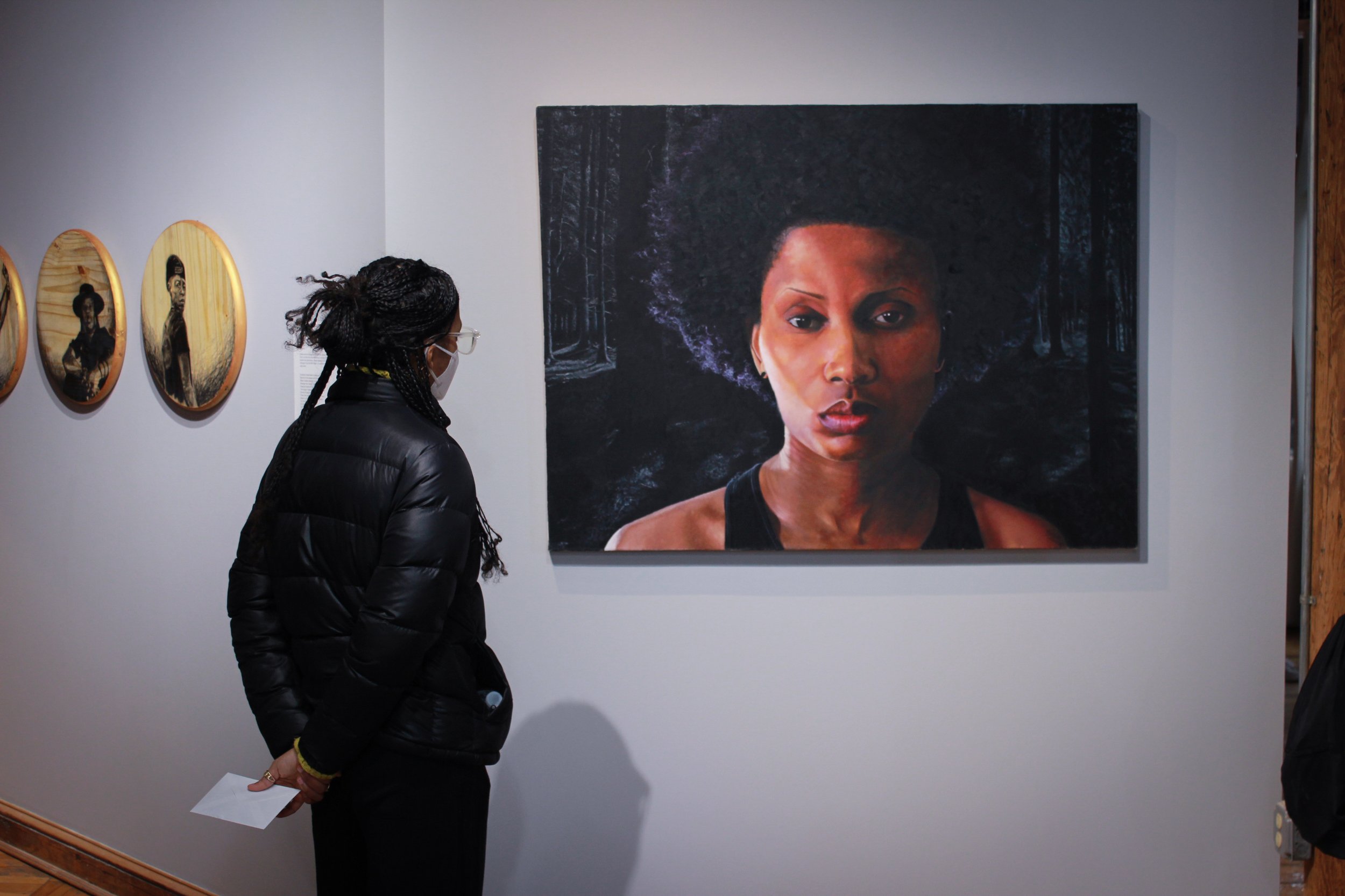 a woman standing in front of a painting of a woman.