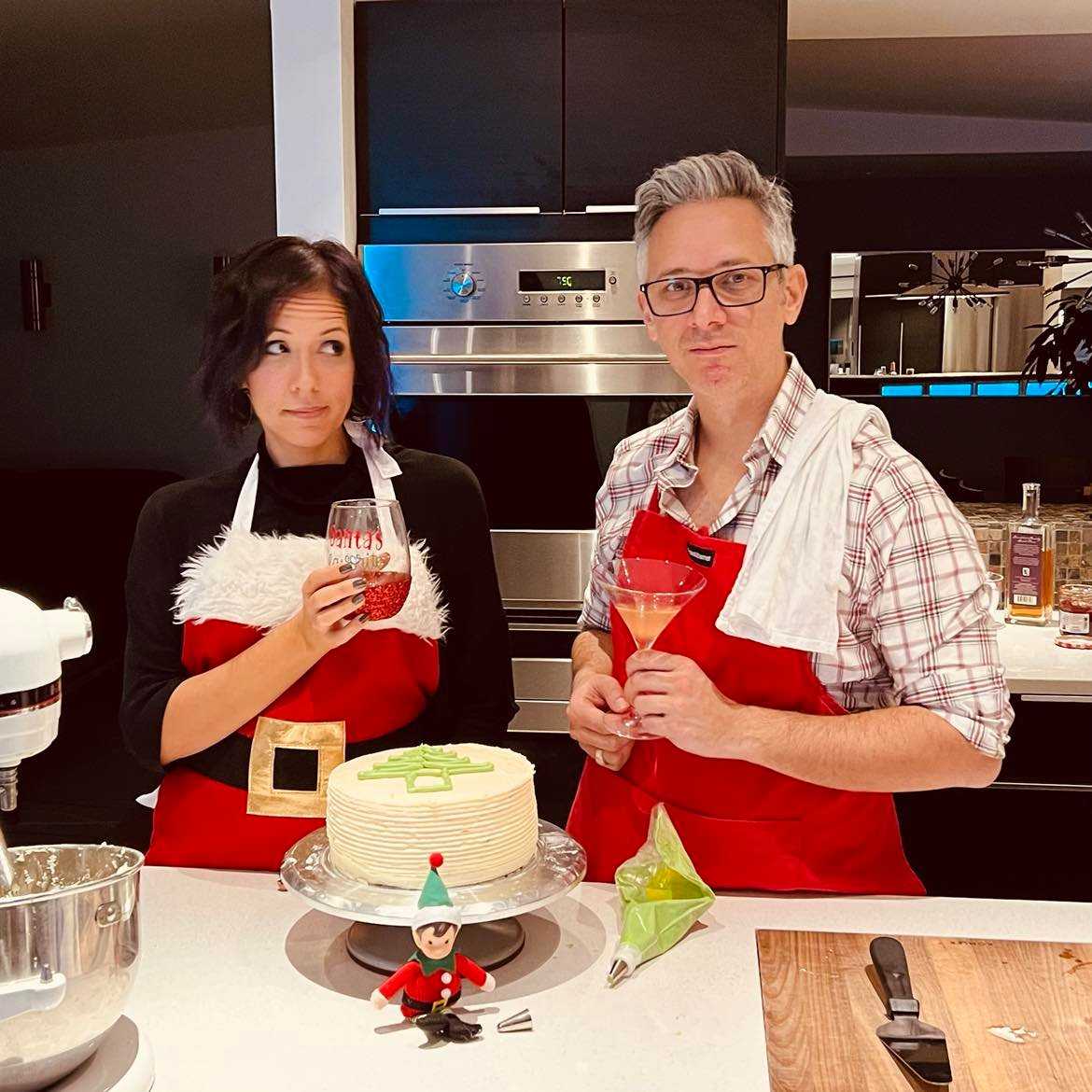 a man and a woman holding wine glasses in front of a cake.