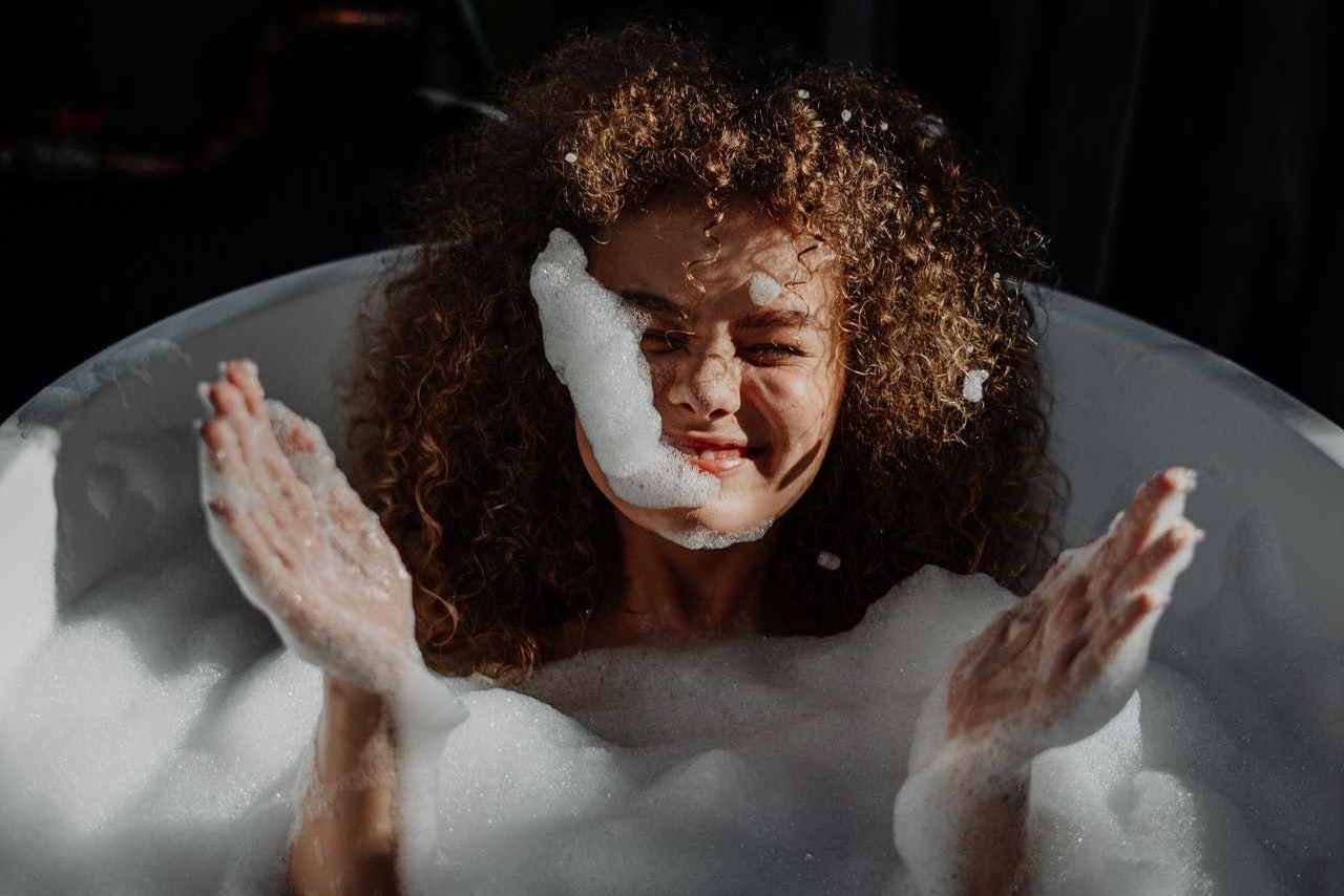 a woman in a bathtub with foam on her face.