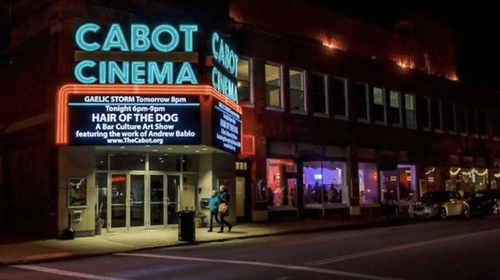 a movie theater lit up at night on a city street.