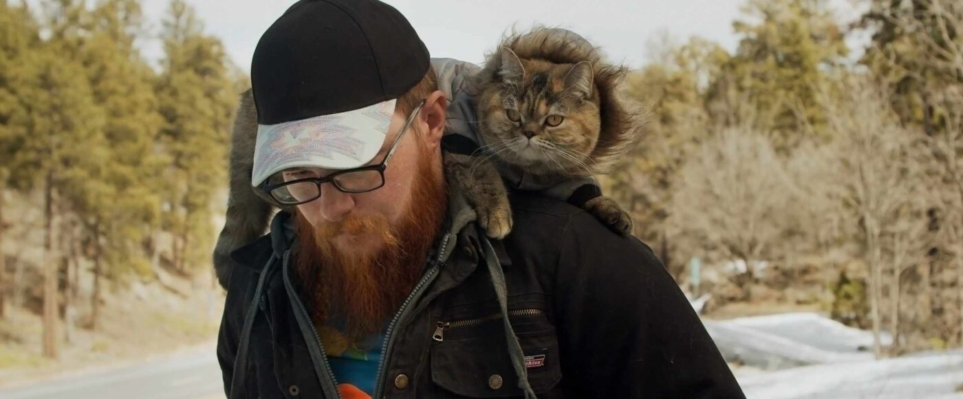 a man with a cat on his shoulders.