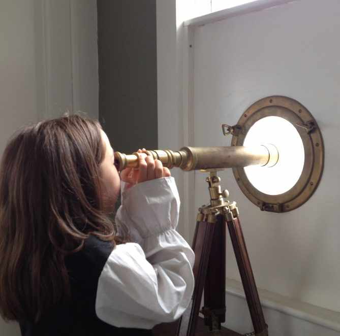 a young girl looking through a telescope into the sky.