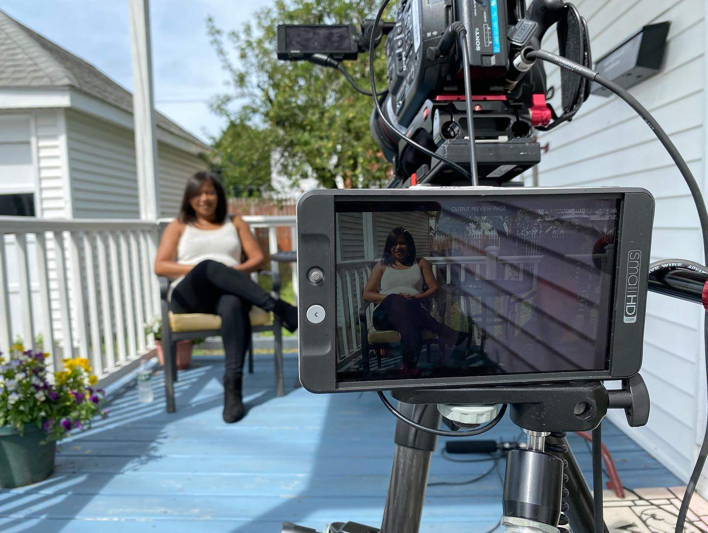 a woman sitting on a porch next to a camera.