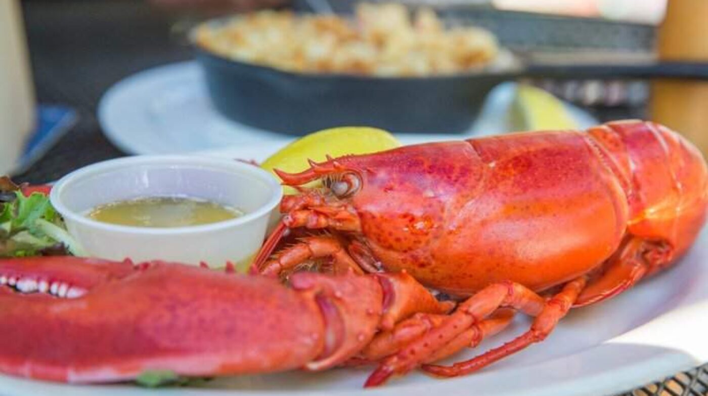 a plate with a lobster and a bowl of dipping sauce.