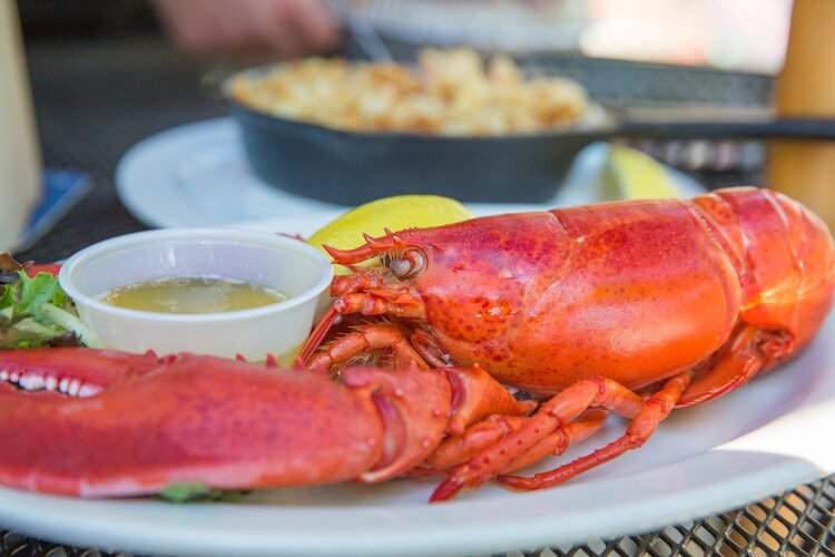 a plate with a lobster and a bowl of dipping sauce.