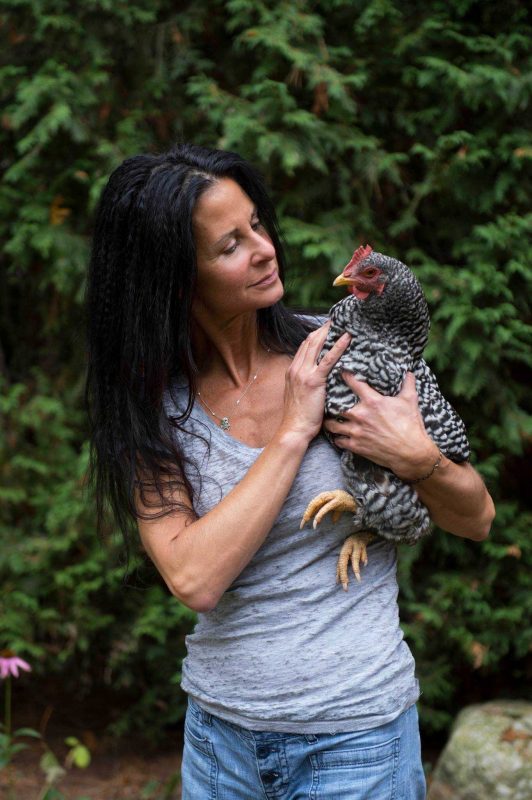 a woman holding a chicken in her hands.