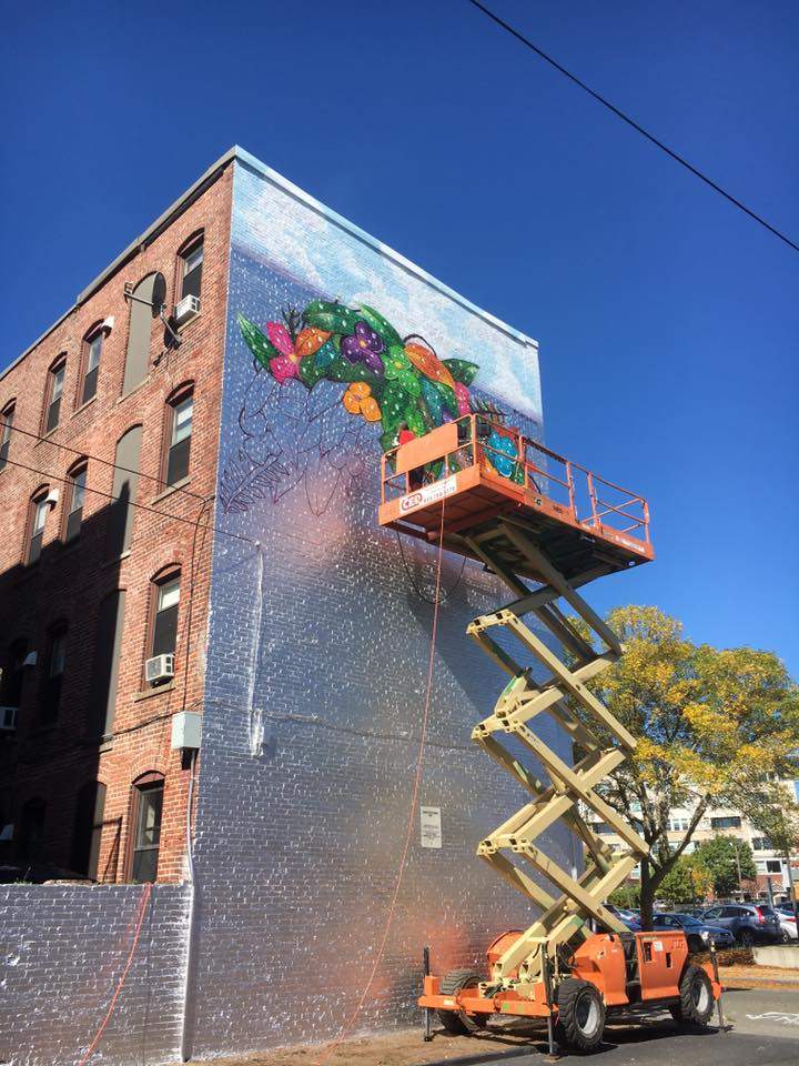 a man is painting a mural on the side of a building.