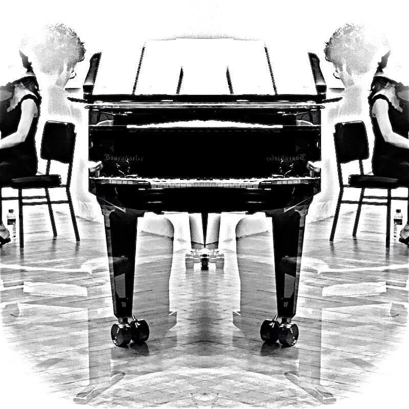 a black and white photo of a woman sitting at a piano.