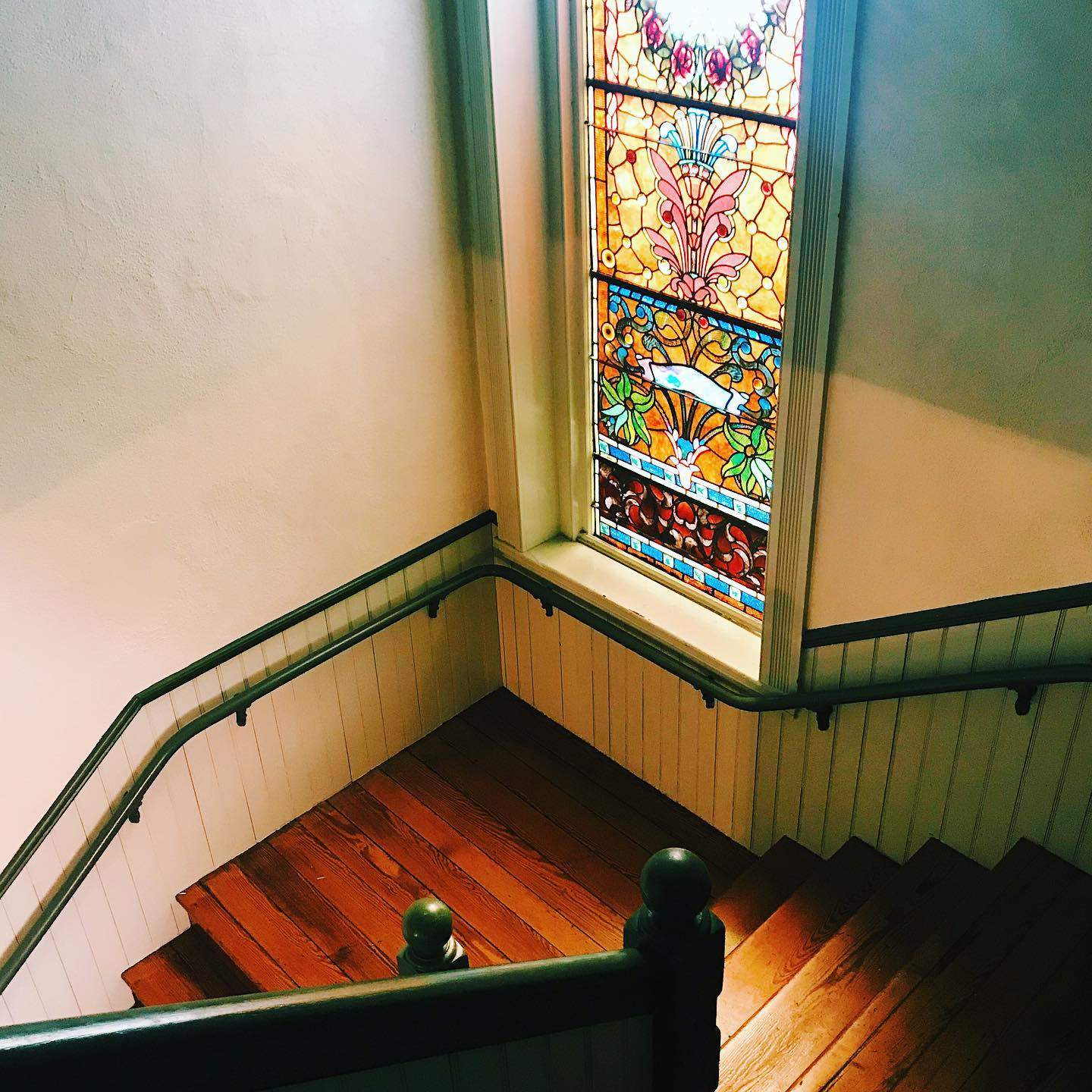 a stained glass window sitting above a wooden staircase.