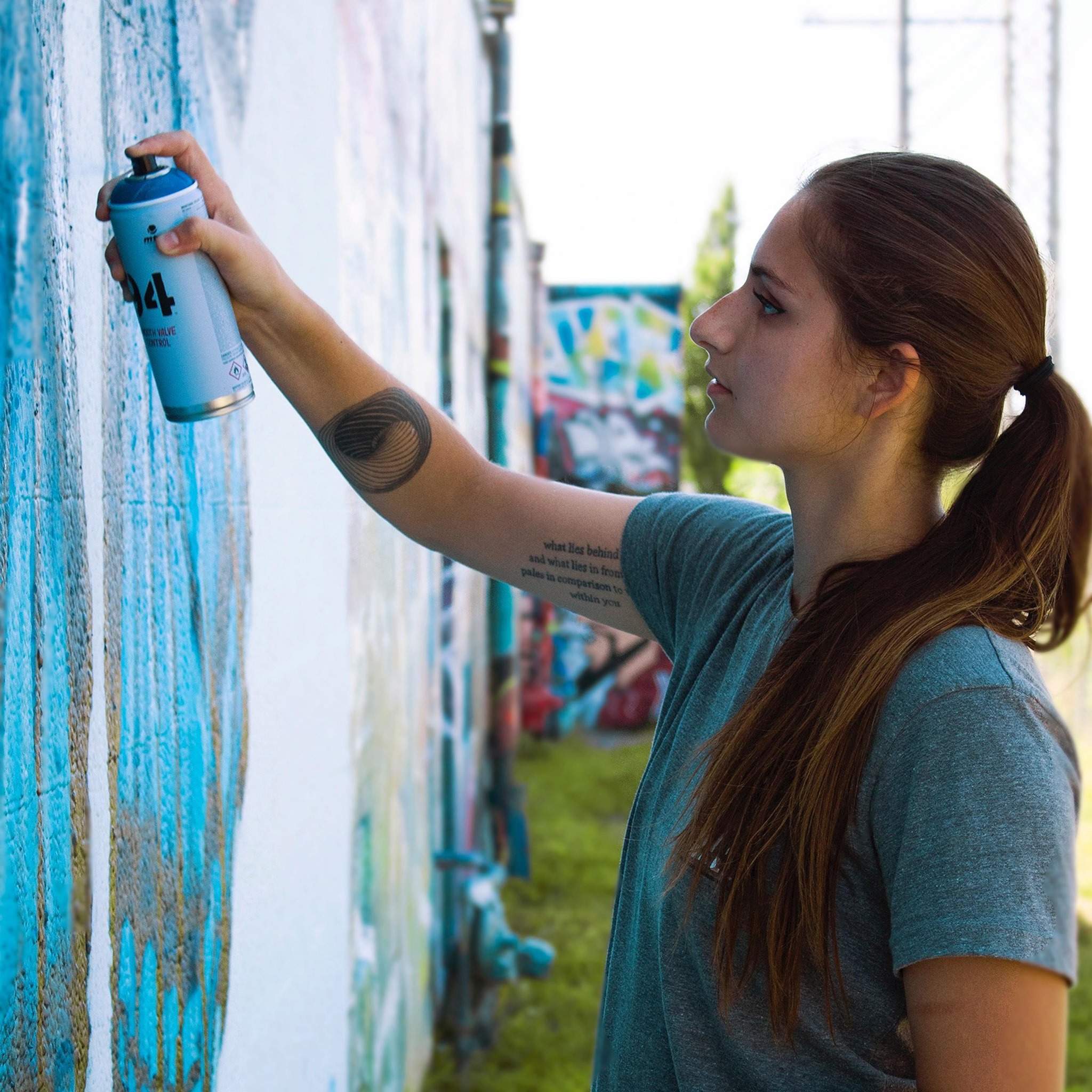 a woman painting a wall with a spray can.