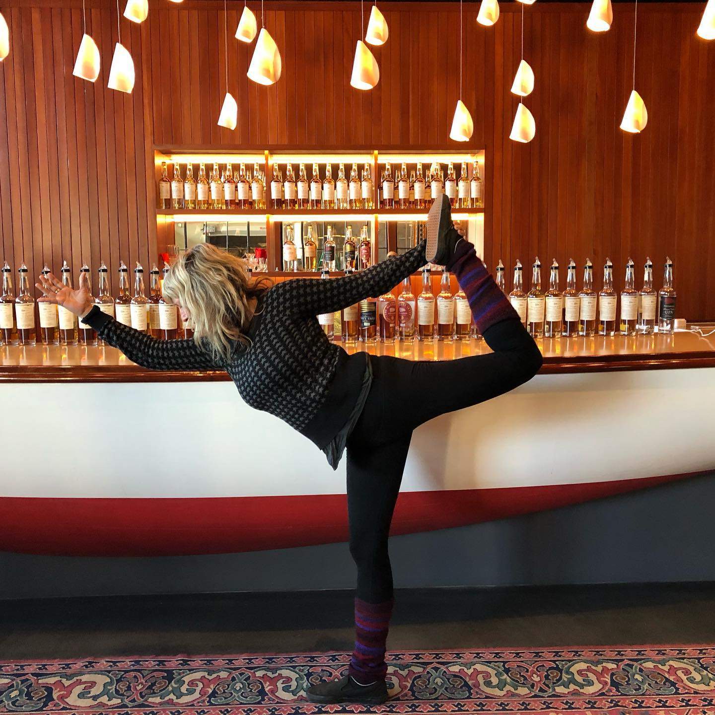 a woman doing a yoga pose in front of a bar.