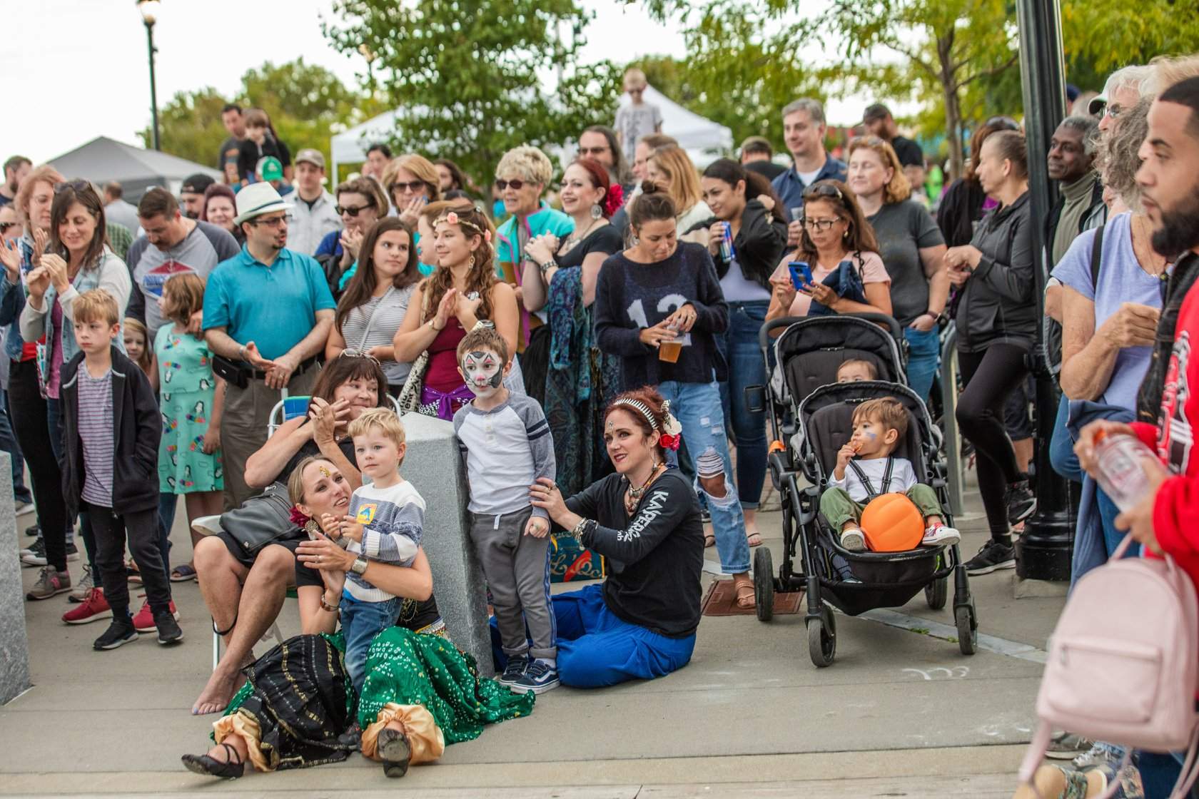 a crowd of people standing around a baby stroller.