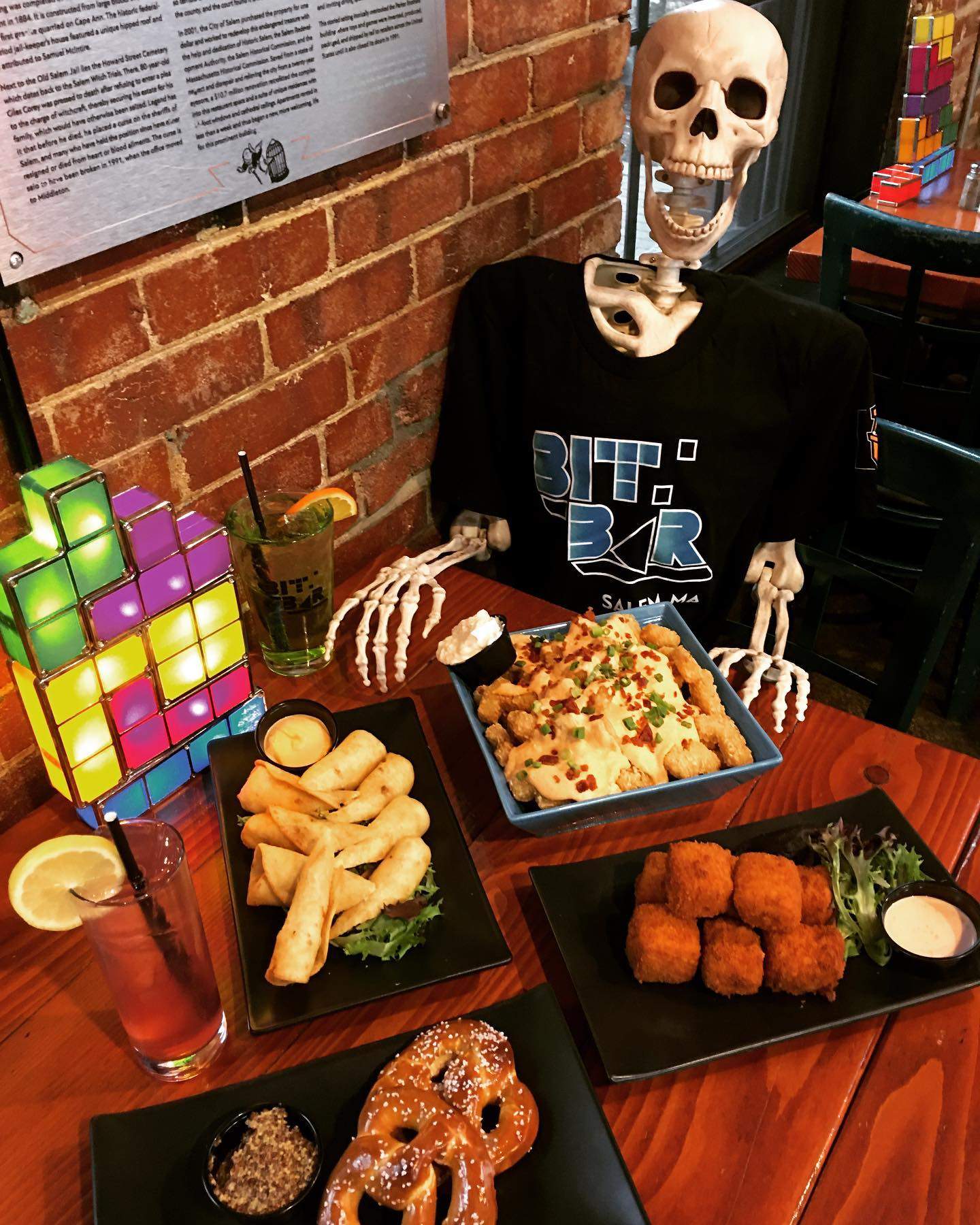 a skeleton sitting at a table with a plate of food.