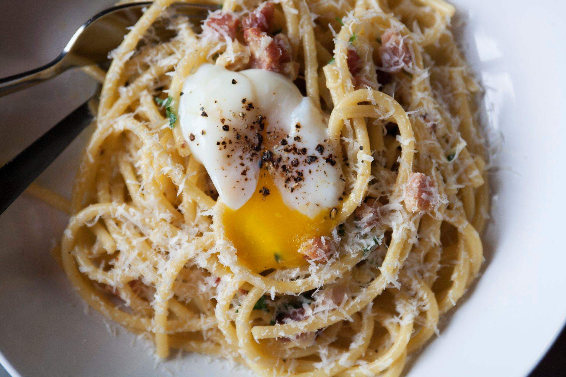 a white plate topped with pasta and an egg.