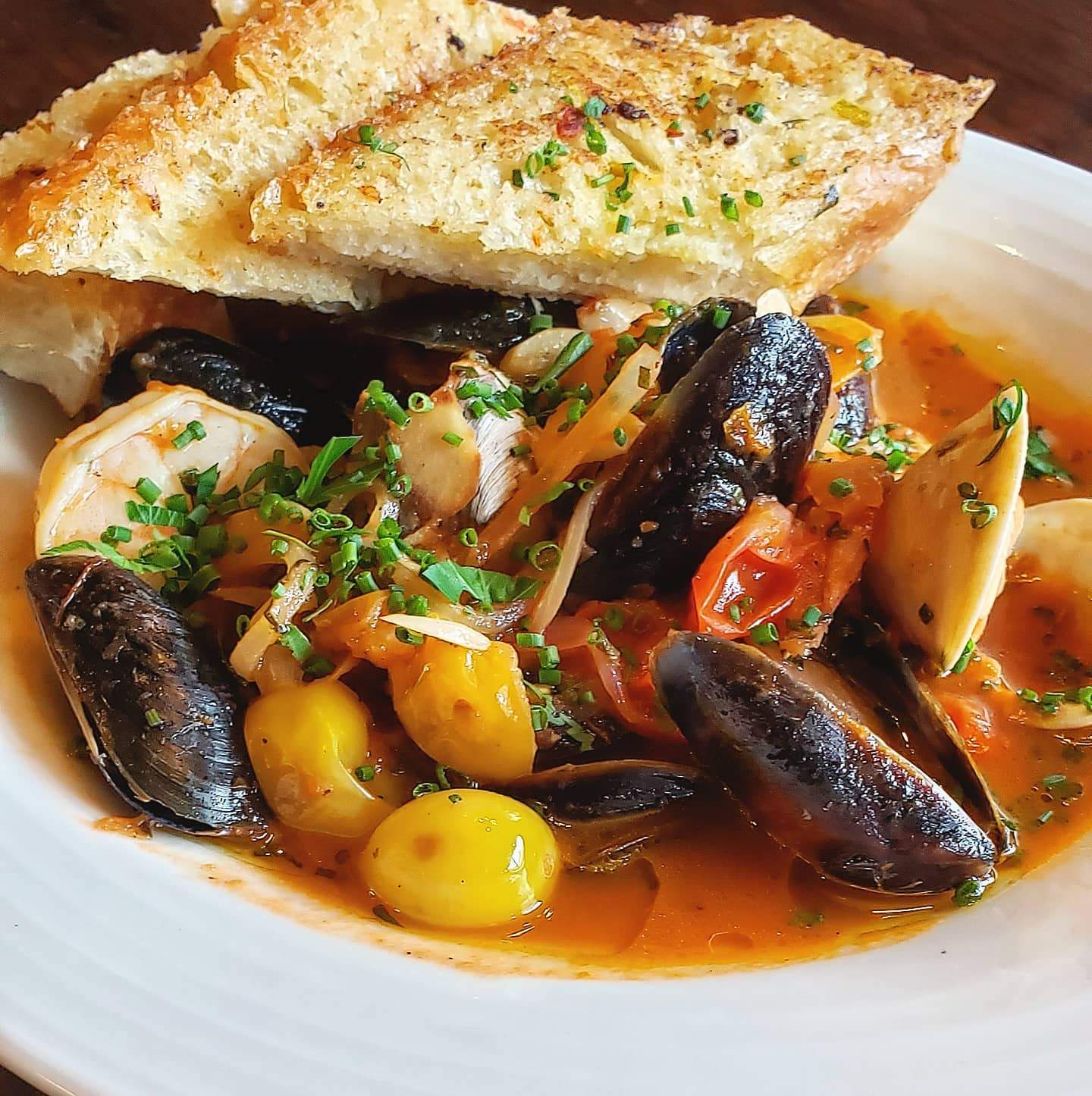 a white plate topped with mussels and a piece of bread.