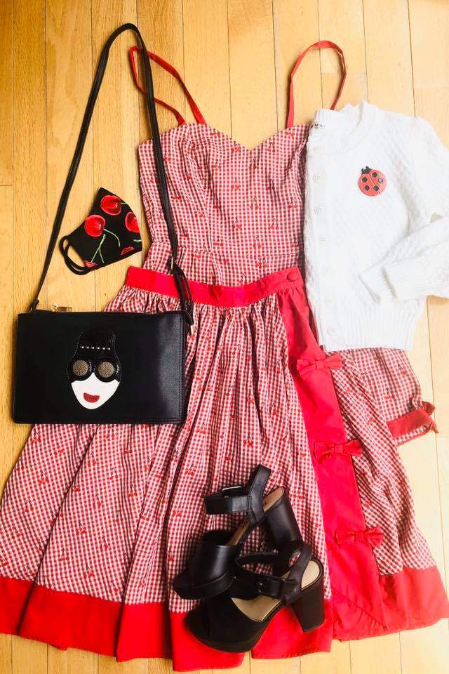 a dress, purse, and shoes are laid out on a wooden floor.