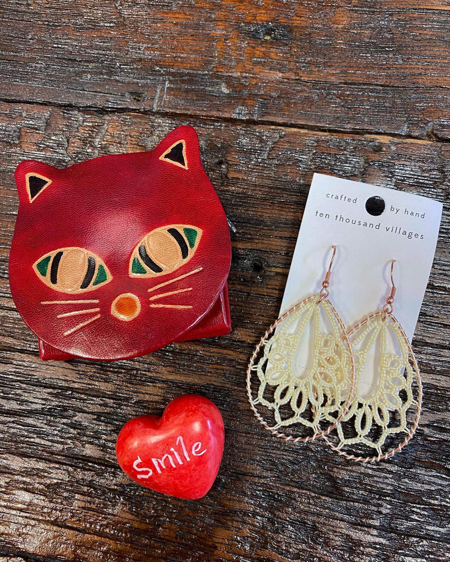 a pair of cat earrings next to a red heart.