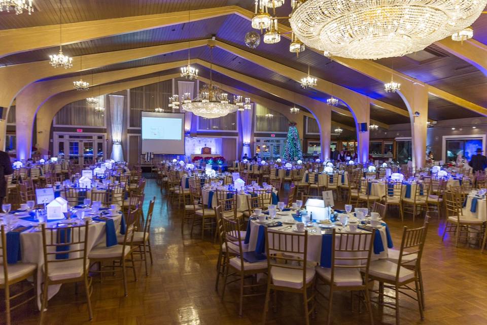 the empty interior of a wedding reception venue is lit with blue and yellow uplighting