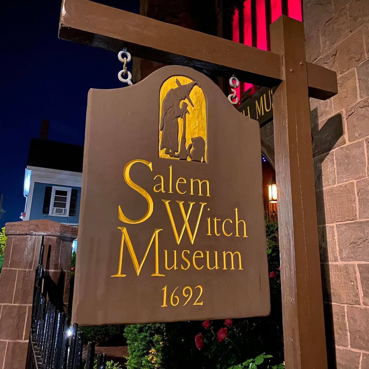 a sign for salem witch museum in front of a brick building.