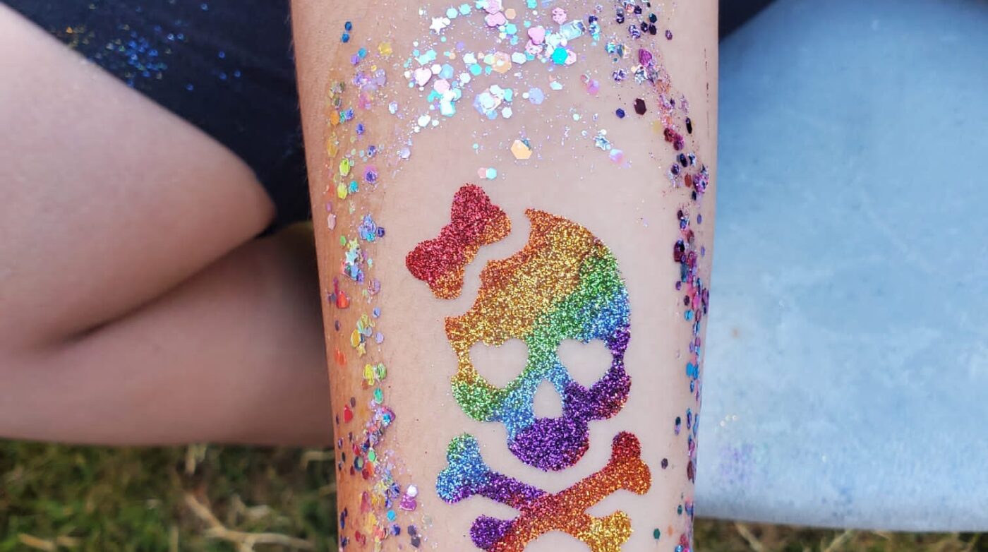 a person's arm covered in glitter with a skull and crossbone on it.