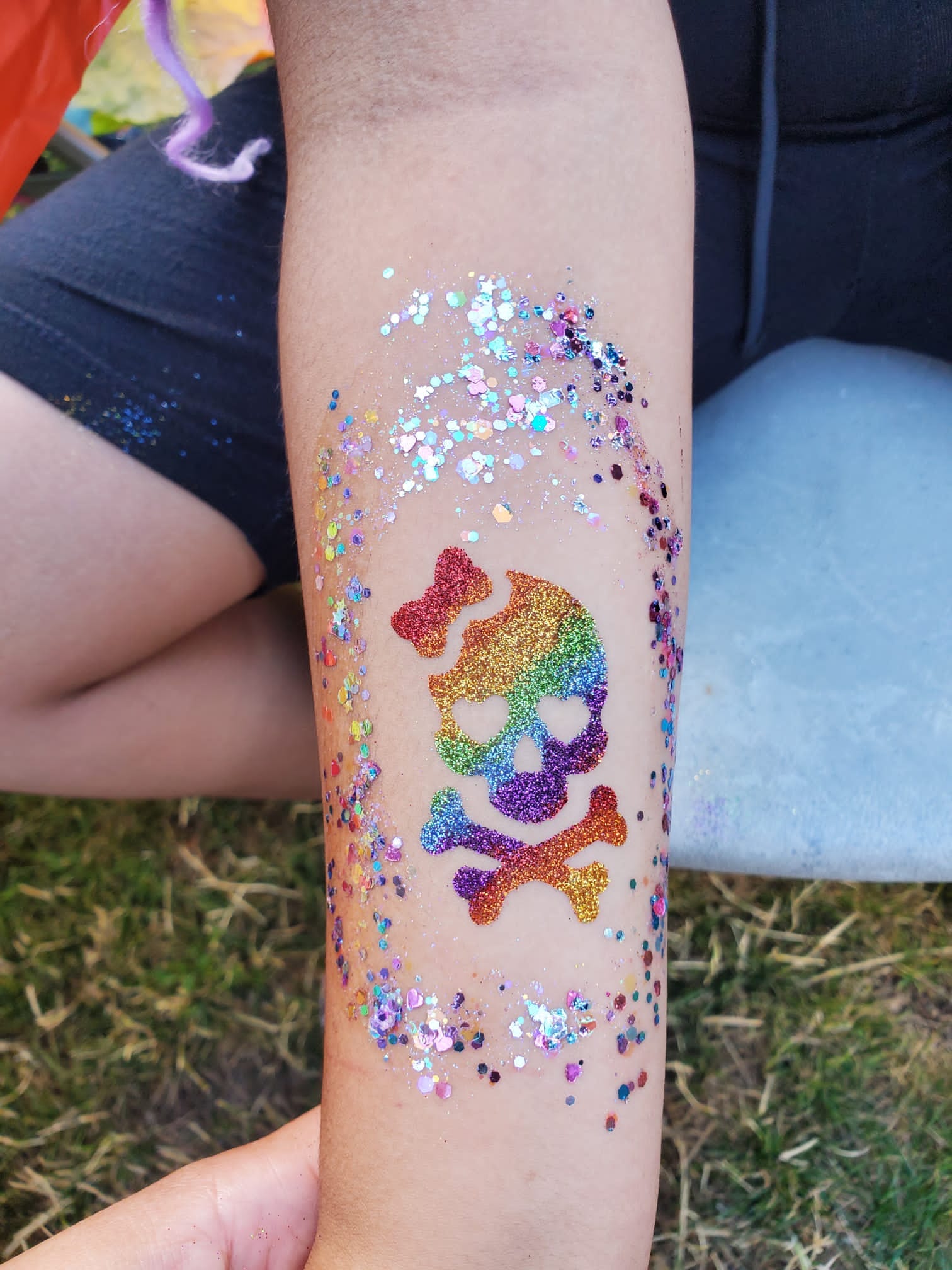 a person's arm covered in glitter with a skull and crossbone on it.