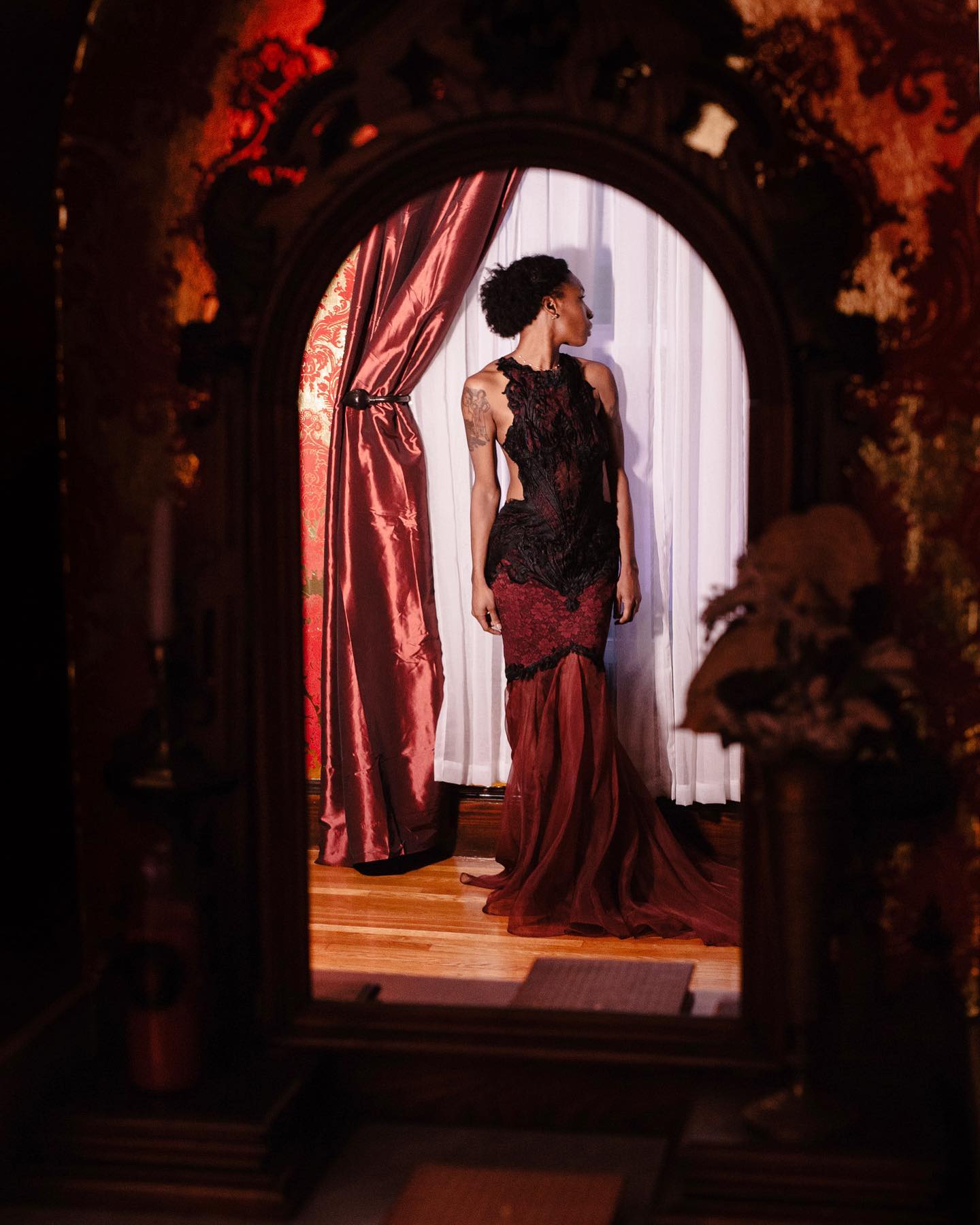a woman in a red dress standing in front of a mirror.