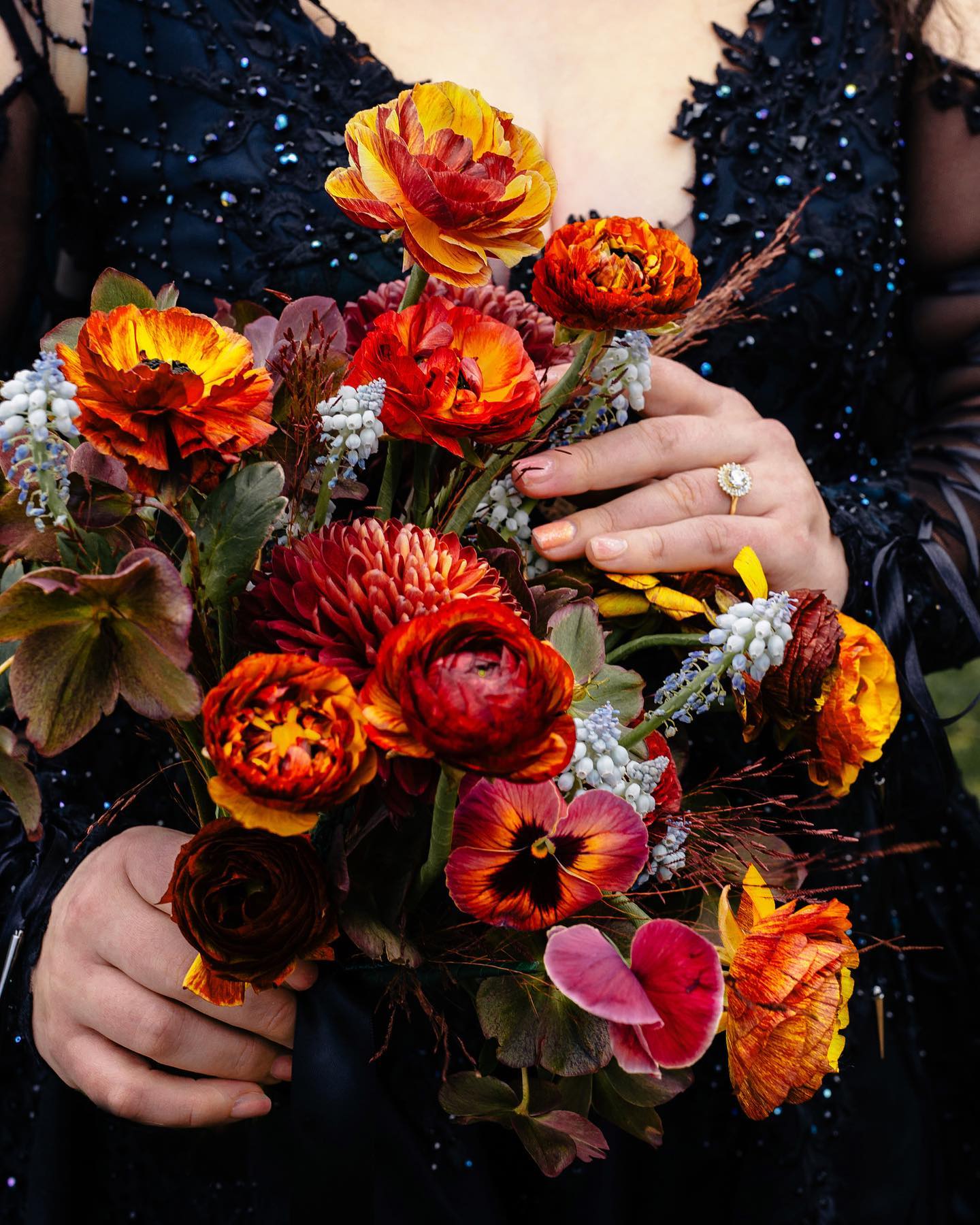 a woman in a black dress holding a bouquet of flowers.