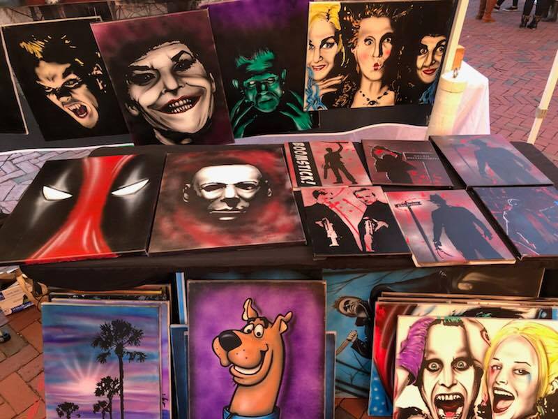 a table topped with lots of paintings of people.